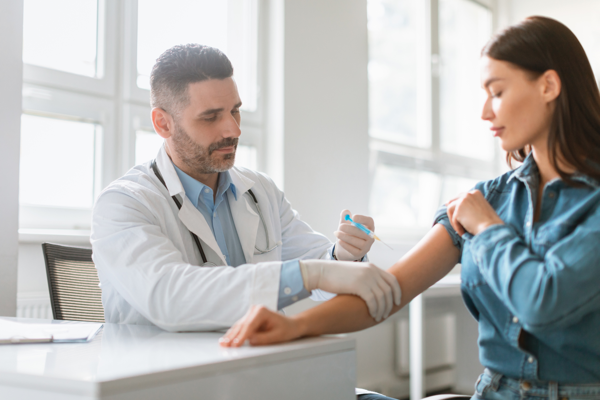 Protecting your health. Young woman getting vaccine shot against viruses, male doctor giving injection to female patient